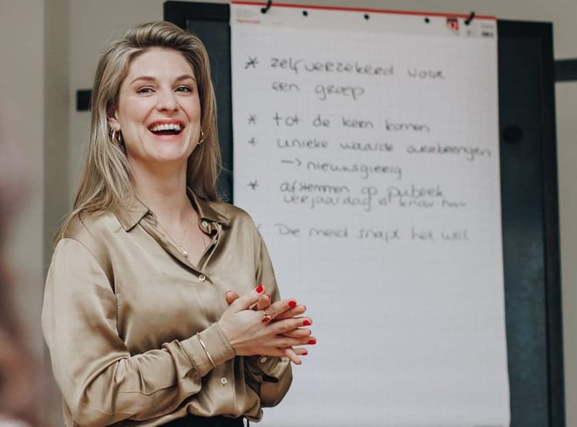 Trainster lacht bij de flip-over tijdens een presentatiecoaching